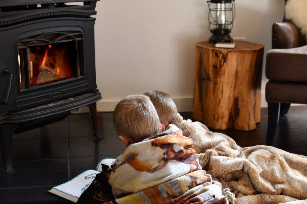 Little boys reading by the wood stove fire while snuggled up in blankets in the winter.