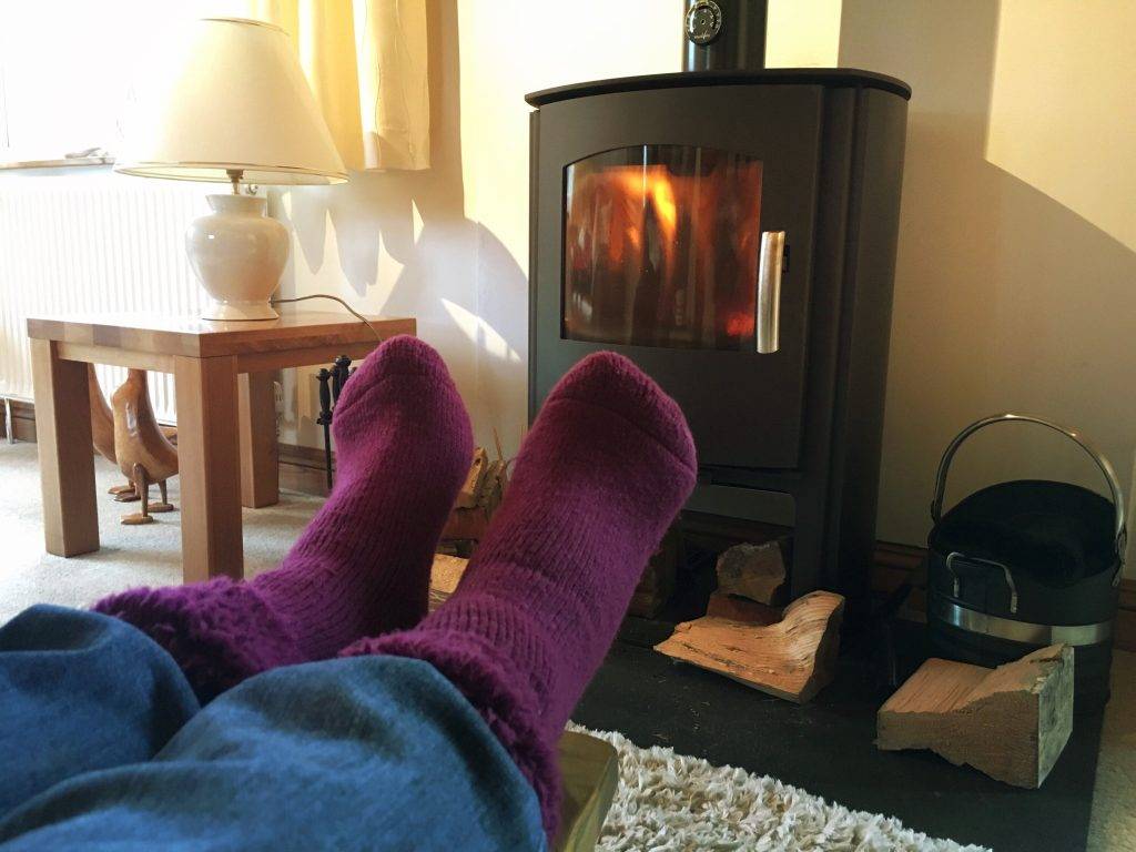 POV Keeping warm and cosy in front of a wood burning stove in winter. Concept of hygge