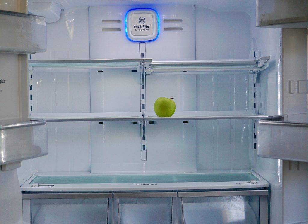 A green apple in an empty refrigerator
