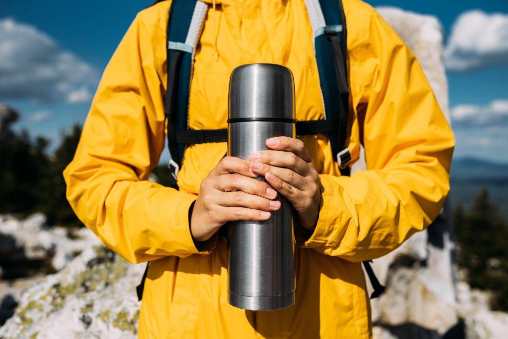 A thermos in the hands of a traveler