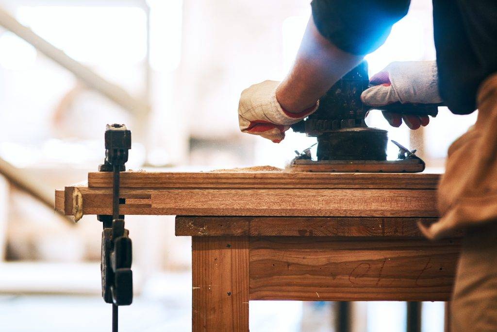 Cropped shot of an unrecognizable carpenter sanding wood with a palm sander inside a workshop