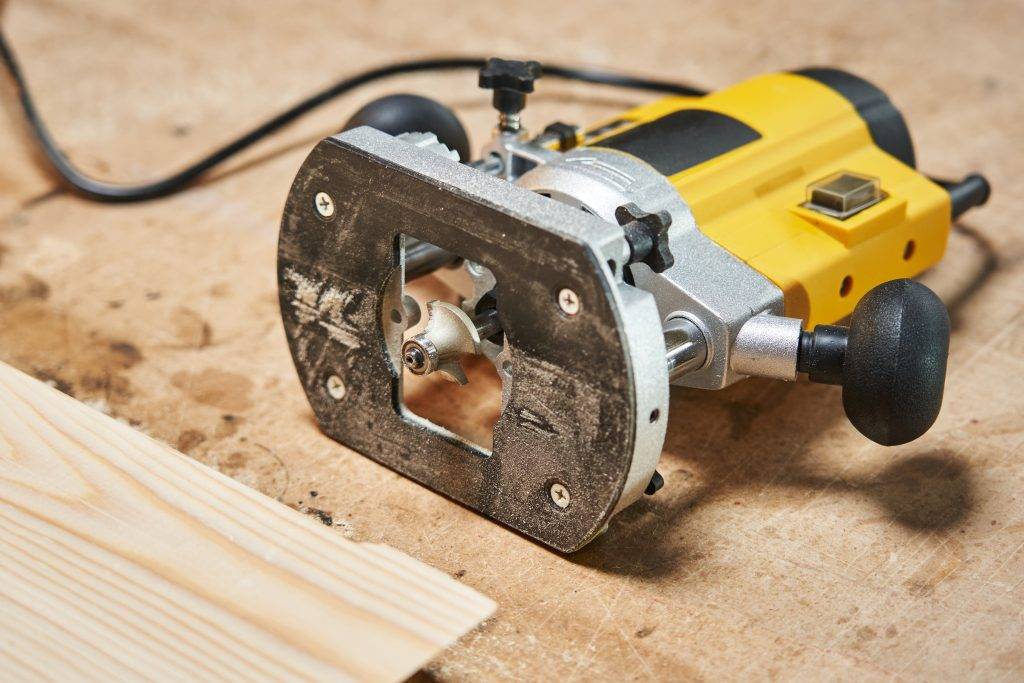 electric wood router lies on a wooden table top. close-up view of the cutter for processing