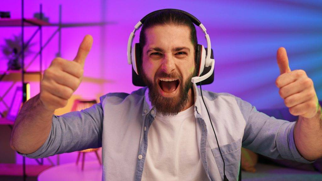 Gamer bearded guy, in a gaming headset, wins a video game. Cybersportsman in a neon room. Lifestyle
