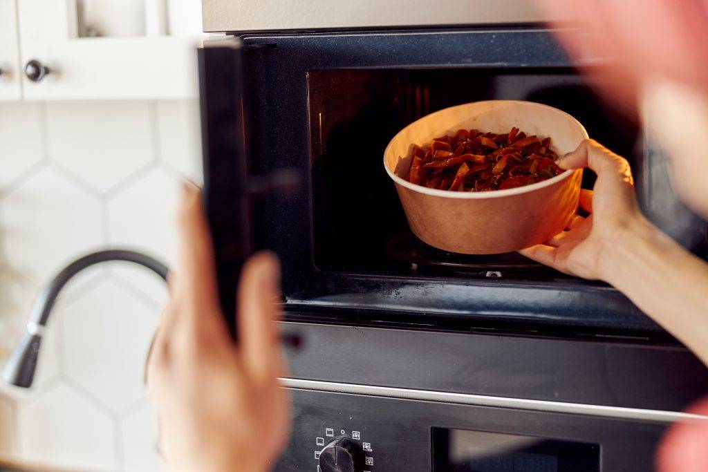 Guy giving foods into the microwave for warm up