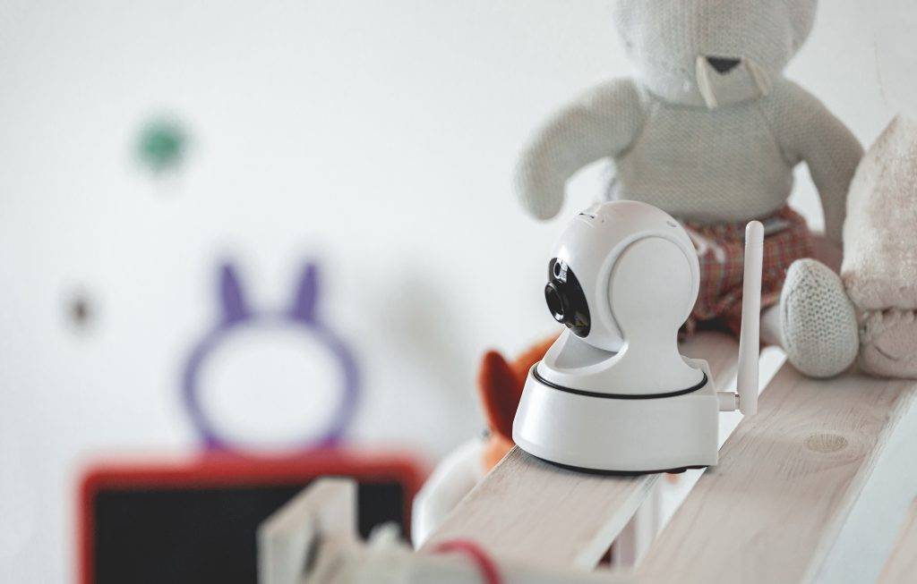 IP camera on the shelf with toys, serving as baby monitor