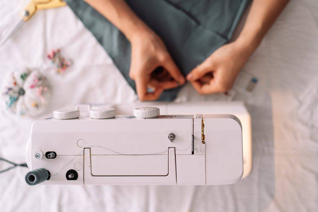 Lady fixes fabric with needles in front of a sewing machine