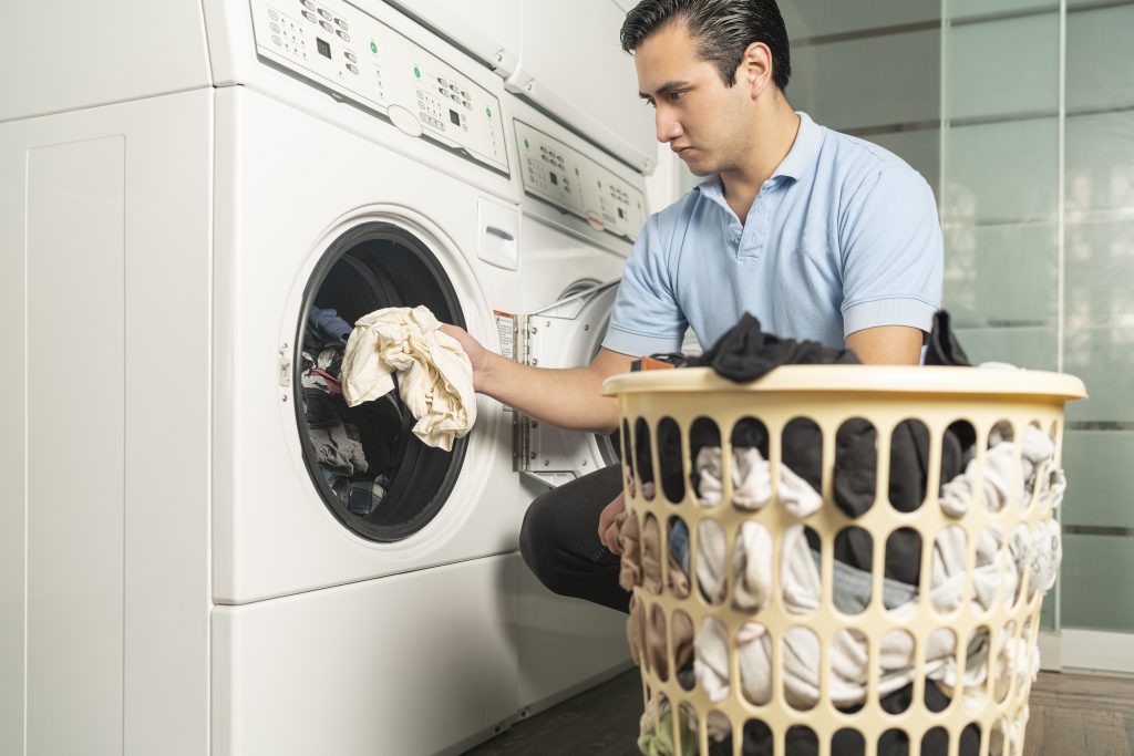 Laundry employee putting clothes in the washer