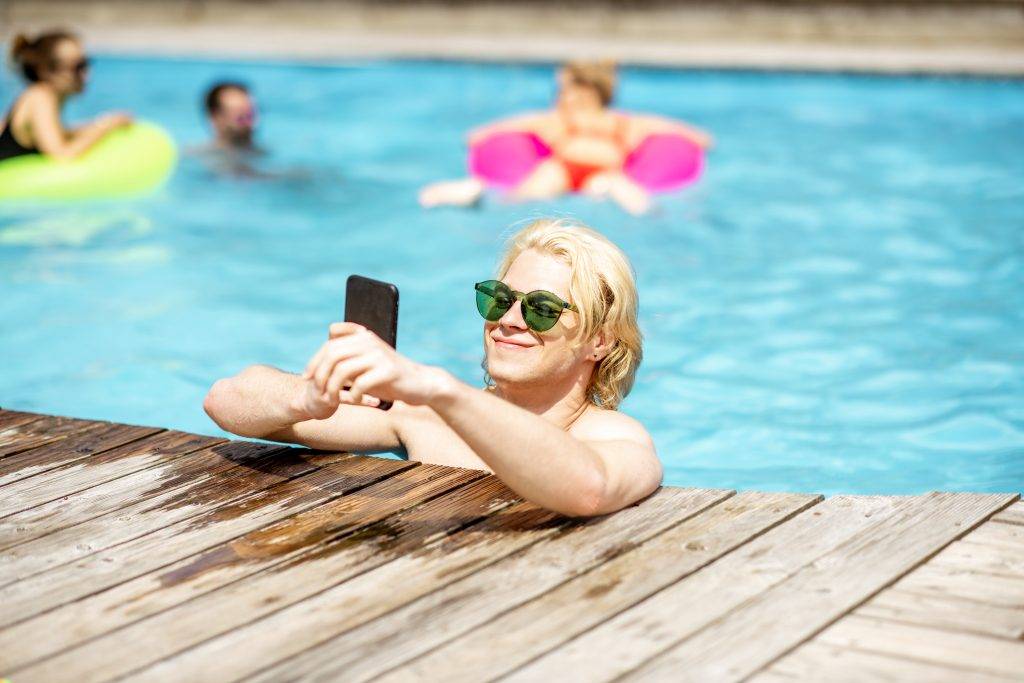 Man with phone in the swimming pool