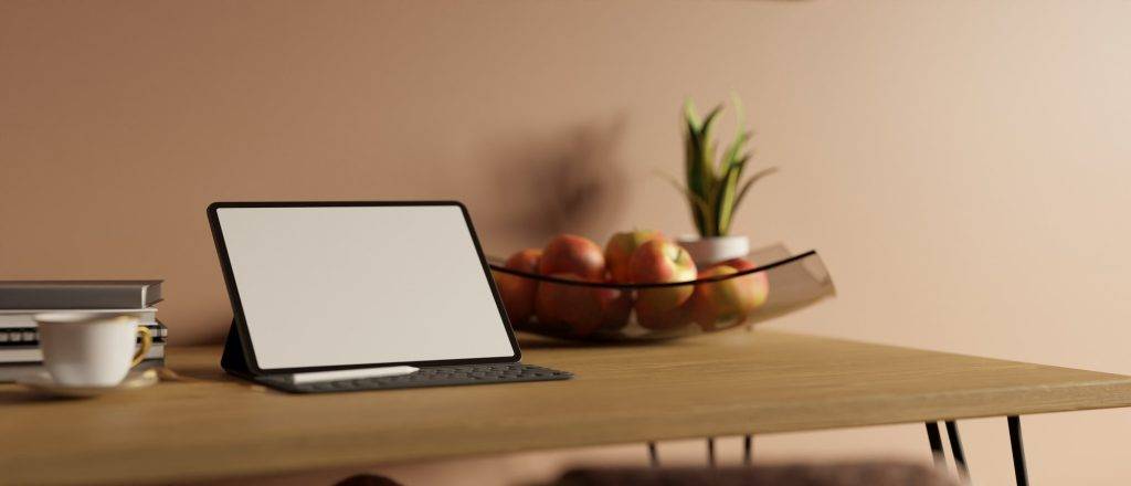 Minimal workspace with tablet mockup and wireless keyboard on wood table over pink pastel wall