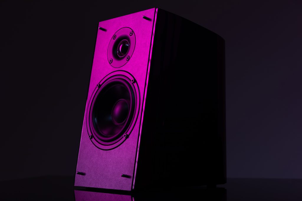 music column with a large speaker on a dark background with lilac backlight close-up