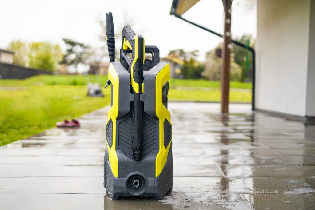 Pressure washer cleaning machine on wet concrete floor