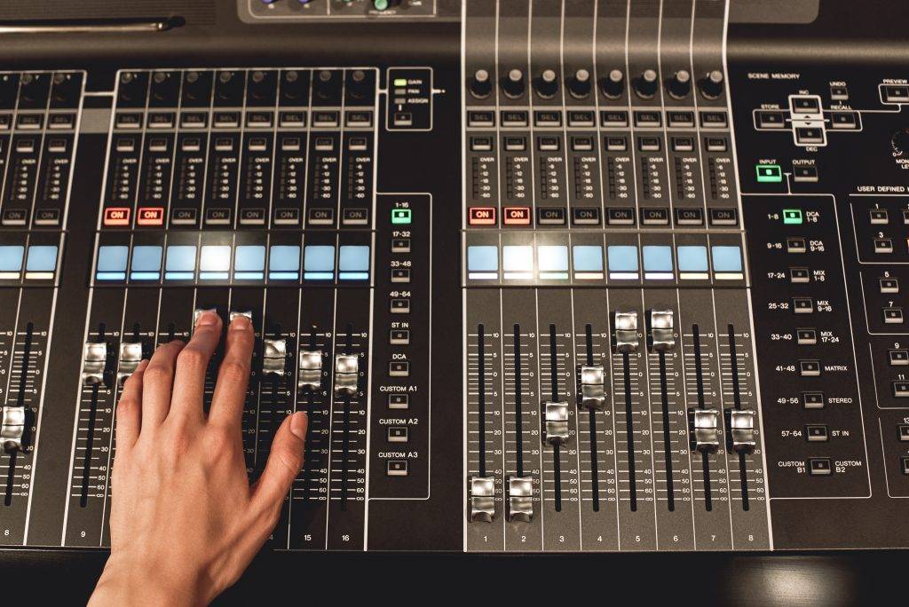 Professional sound control. Close-up view of male hand mixing sounds on digital audio mixing console