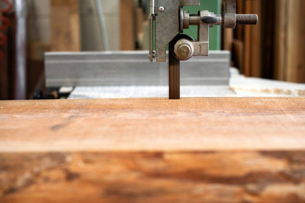 Sawing wood using a band saw in a workshop