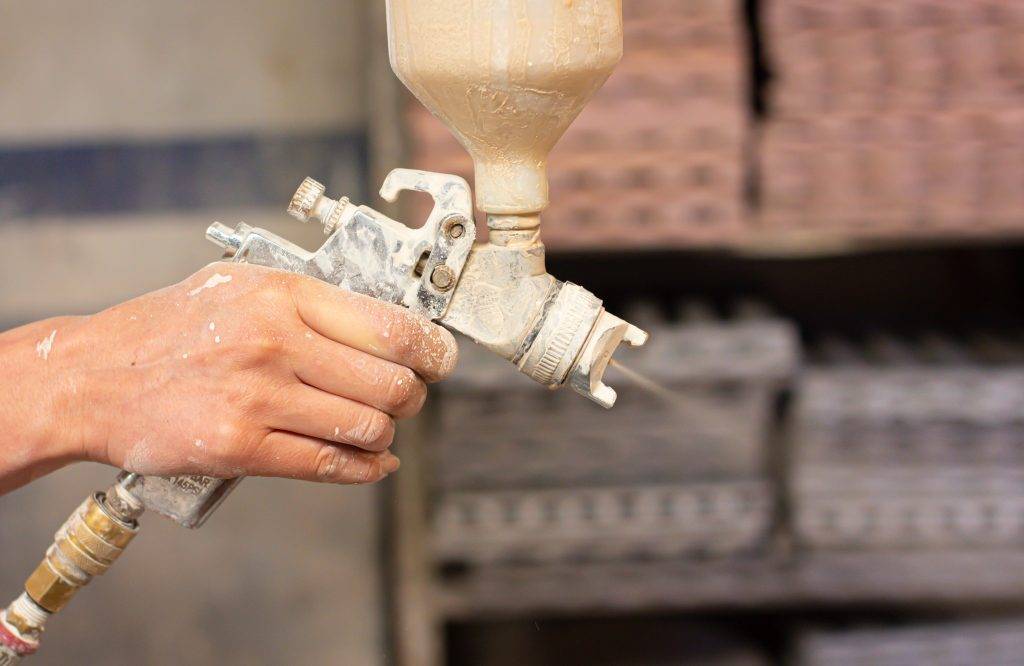 Shallow focus shot of human hands holding a paint sprayer in the workshop