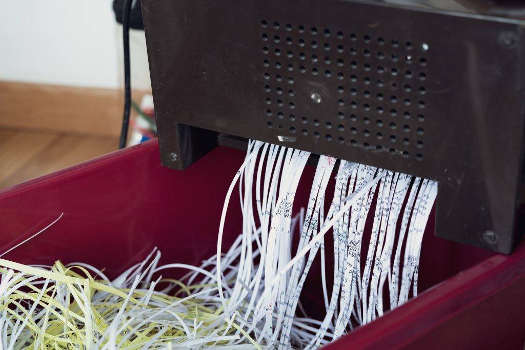 Shredding papers coming out from the machine. Shredding documents for security