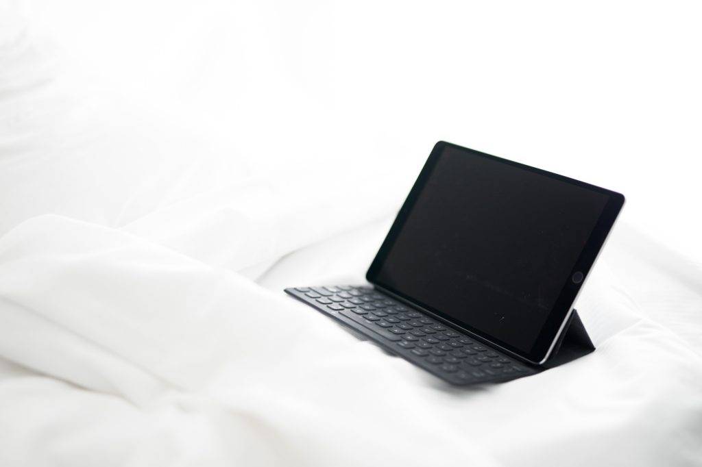 Tablet ipad computer technology tablet isolated on a empty bed with crisp white cotton sheets simple