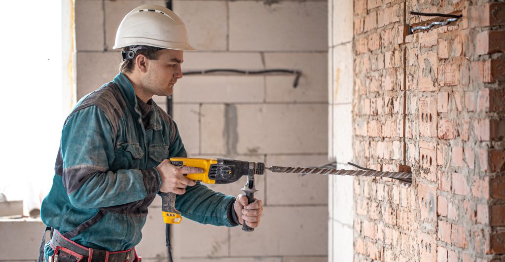 The builder works with a drill in working form.
