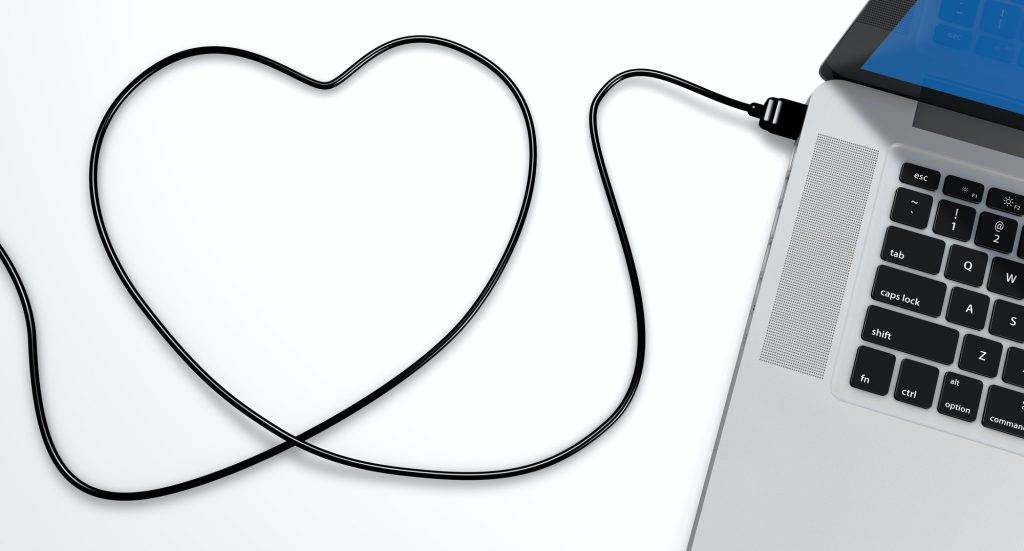 Usb cable plugged into a laptop, with the shape of a heart, on a white background