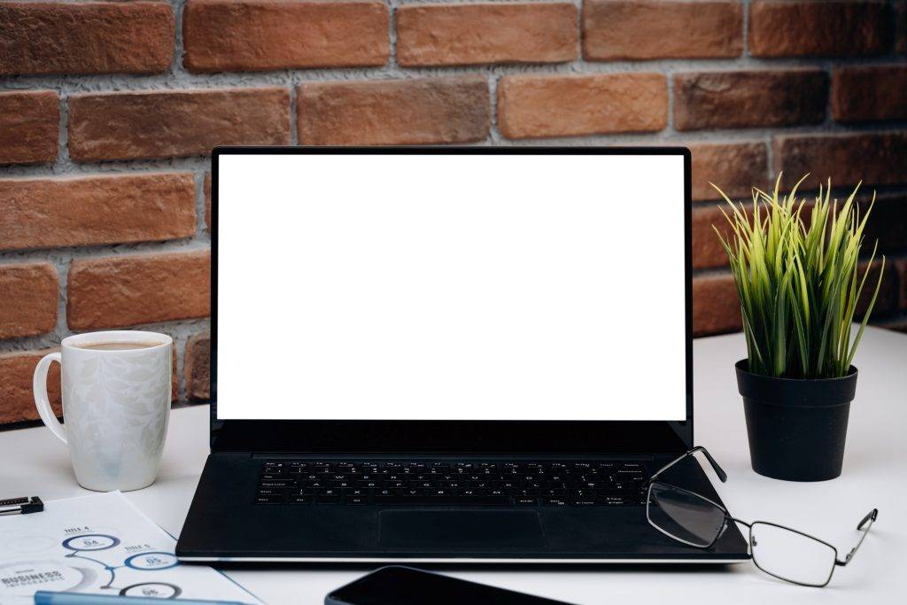 Working desk with blank screen laptop.