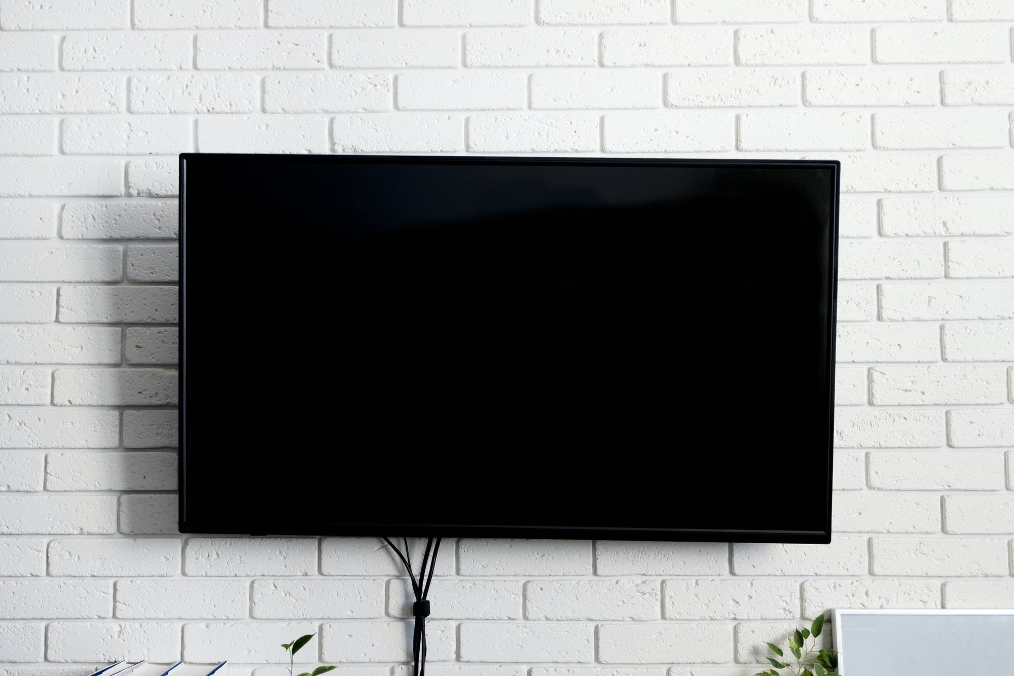 Led tv black color on brick white wall, indoors. Living room. Concept rest at home
