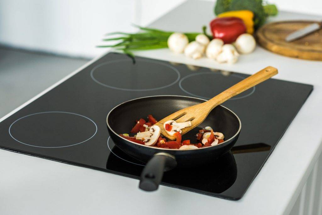 frying pan with appetizing vegetables on electric stove in kitchen