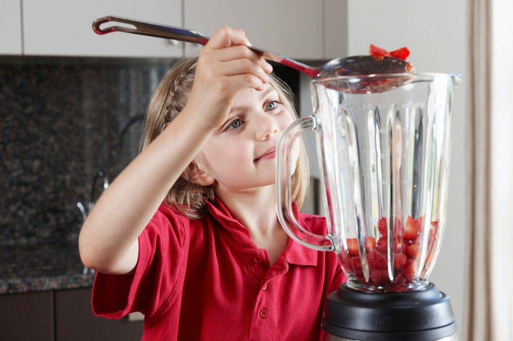 Girl putting fruit in blender