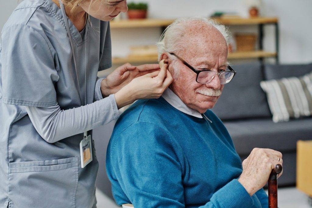 Caregiver helping to wear hearing aid