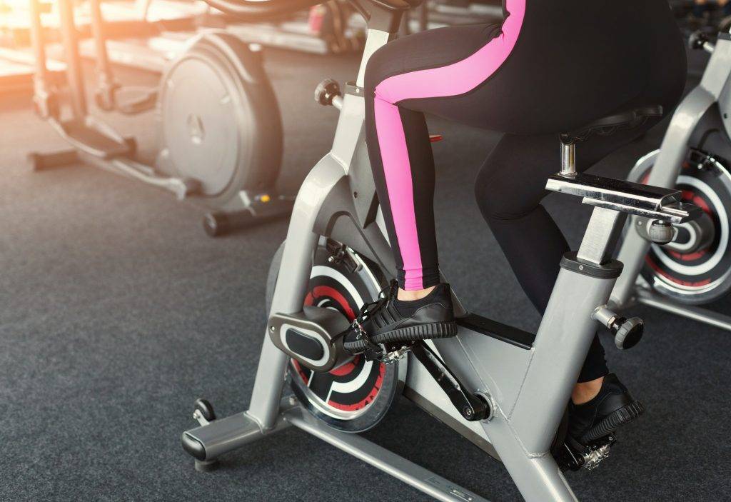 Woman's legs on exercise bikes in fitness club, healthy lifestyle